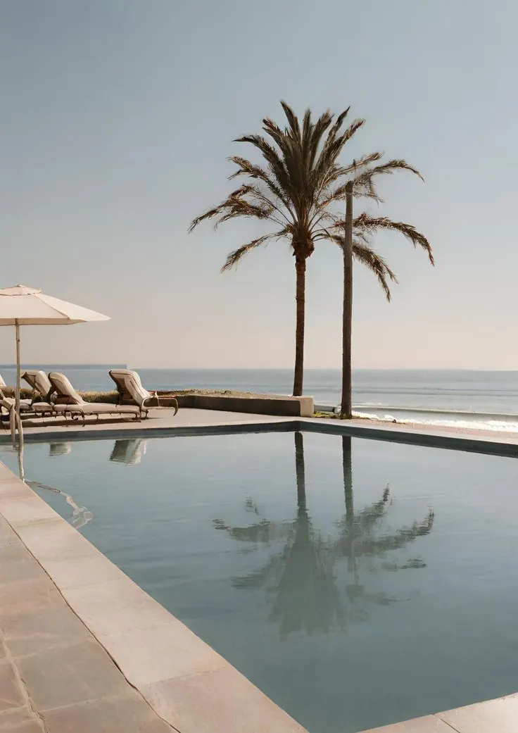 Sun loungers beside a pool looking out to the sea in Marbella