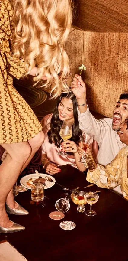 Friends laughing over wine at a banquette table